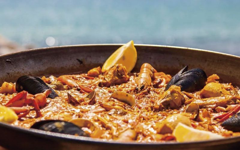 Paella tradicional con el mar de Ibiza de fondo
